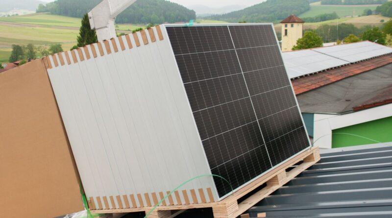 Palette mit Solarmodulen wird mit einem Kran auf ein Dach gehoben – ideal für den Einkauf im Solar Großhandel.