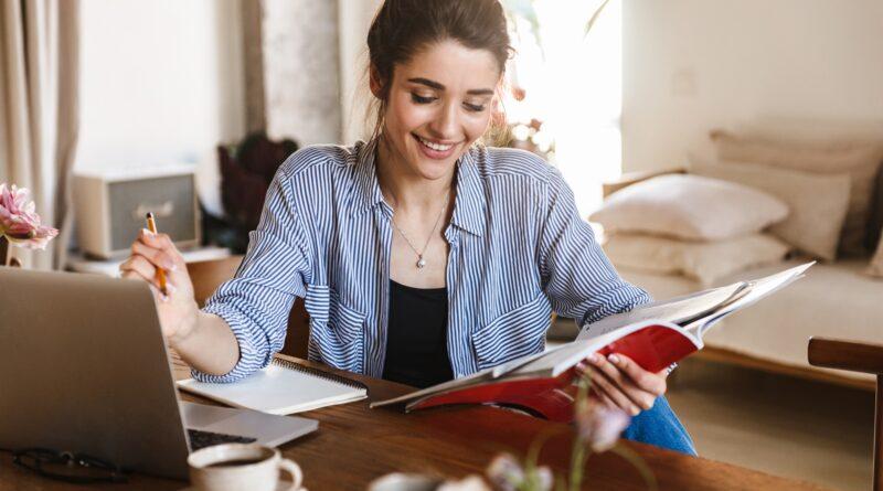 Studentin schreibt mit Laptop und Heften | Ghostwriter Masterarbeit