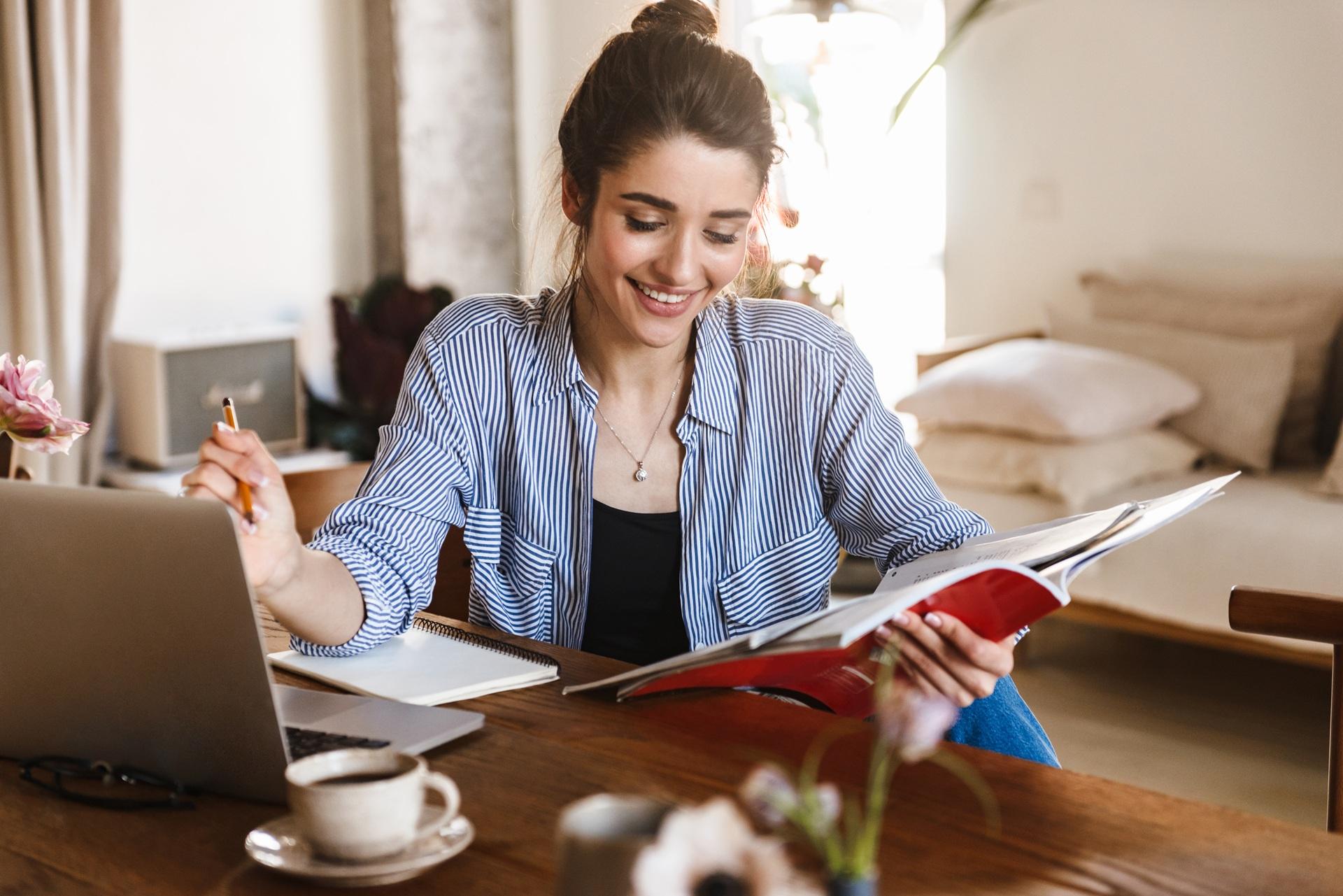 Studentin schreibt mit Laptop und Heften | Ghostwriter Masterarbeit